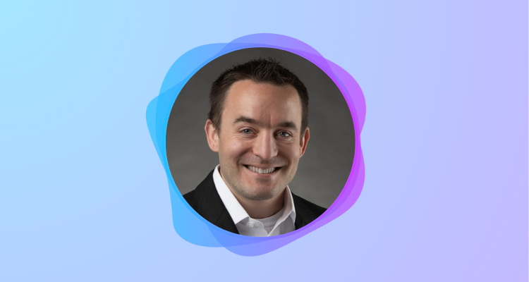 A photograph of Luke Philips surround by a circular blue and purple frame. Luke is smiling.